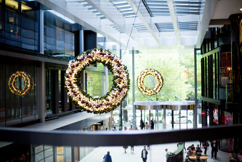 Lit-up Christmas wreaths hanging in a Collins Square atrium