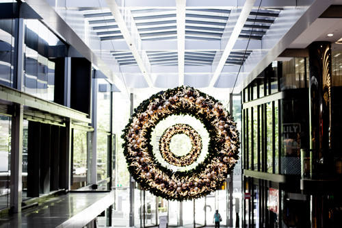 Lit-up Christmas wreaths hanging in a Collins Square atrium